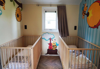 Babykamer met twee wiegjes en kleurrijke bijenmuurschilderingen, Baby cottage, Kaatsheuvel, Nederland.
