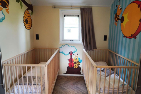 Børneværelse med to tremmesenge, farverige vægmalerier med bier og bikube, Baby cottage, Kaatsheuvel.