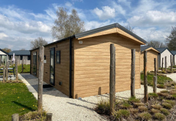 Lodge Berkel moderno con rivestimento in legno, circondato da piccoli giardini e cielo nuvoloso.