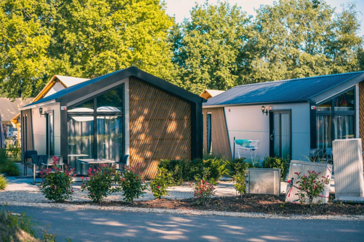 Modern Berkel lodge cabins in Kaatsheuvel, Netherlands, with lush green trees and bright blooming plants.