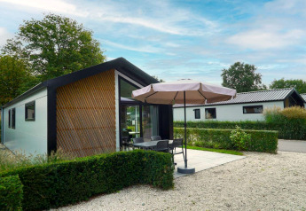 Buitenaanzicht van lodge Berkel in Kaatsheuvel, Nederland, met terras, tuinmeubilair en parasol.