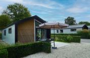Außenansicht der Berkel-Lodge in Kaatsheuvel, Niederlande, mit Terrasse, Gartenmöbeln und Sonnenschirm.