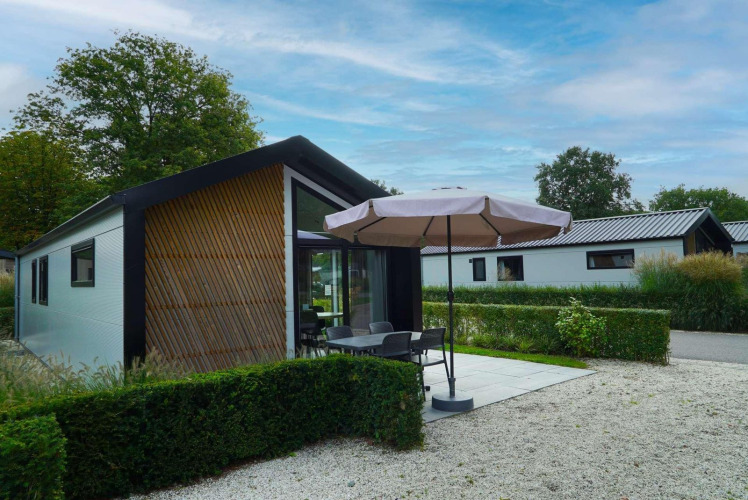 Außenansicht der Berkel-Lodge in Kaatsheuvel, Niederlande, mit Terrasse, Gartenmöbeln und Sonnenschirm.