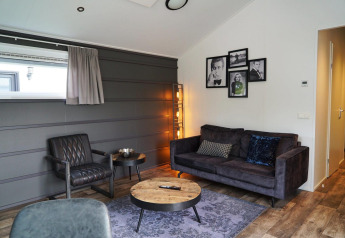 Interno glamping moderno a Berkel con divano, poltrona, tavolino e quadri decorativi sulla parete.