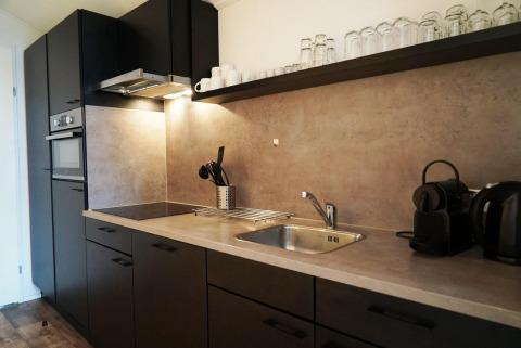 Cocina moderna en la lodge Berkel, Kaatsheuvel, Países Bajos, con gabinetes oscuros y fregadero.