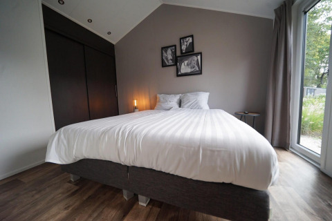Modernes Schlafzimmer in der Berkel Lodge, Kaatsheuvel, Niederlande, mit großem Bett und Fensterausblick.