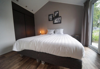 Dormitorio moderno en Berkel Lodge, Kaatsheuvel, Países Bajos, con cama grande y ventana al exterior.