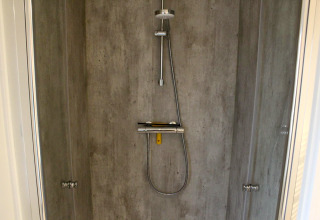 Douche moderne avec murs aspect béton et pommeau pluie au lodge Berkel à Kaatsheuvel, Pays-Bas.
