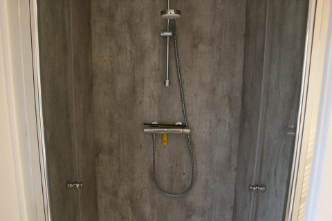 Moderne Dusche mit Betonwänden und Regendusche im Lodge Berkel in Kaatsheuvel, Niederlande.