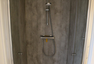 Moderne Dusche mit Betonwänden und Regendusche im Lodge Berkel in Kaatsheuvel, Niederlande.