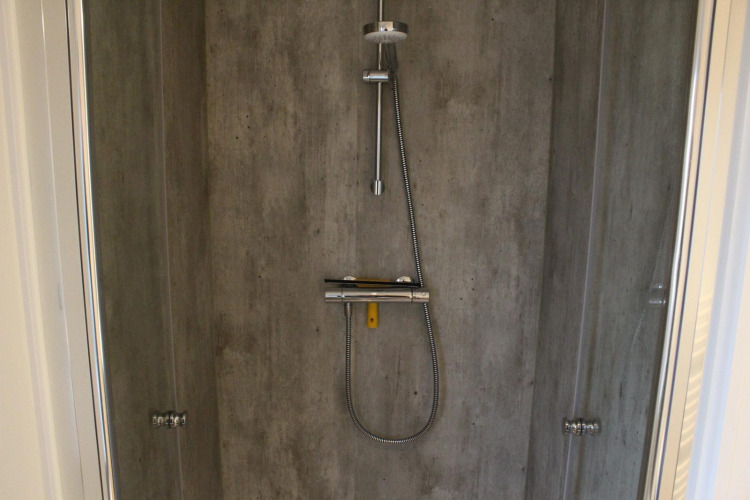 Modern shower with concrete-style walls and rainfall showerhead at Lodge Berkel in Kaatsheuvel, Netherlands.