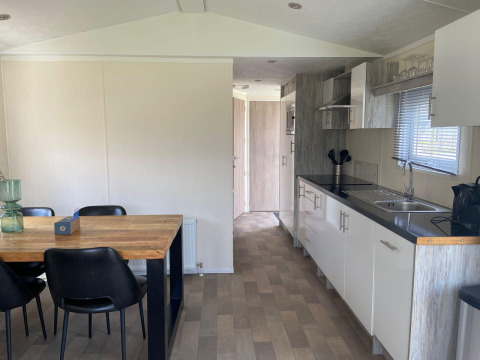 Cocina y comedor modernos en la cabaña Berkel en Kaatsheuvel, Países Bajos, con mesa y sillas negras.