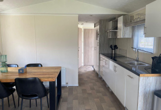 Cocina y comedor modernos en la cabaña Berkel en Kaatsheuvel, Países Bajos, con mesa y sillas negras.