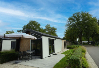 Lodge moderno con terraza y sombrilla en Berkel, Kaatsheuvel, Países Bajos, rodeado de vegetación.