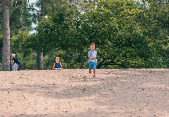 Zwei Kinder spielen im Sand vor Bäumen im Pavilion Maximaal, Kaatsheuvel in den Niederlanden.
