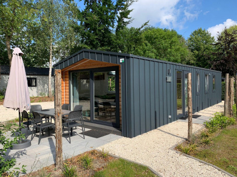 Moderne Berkel-Lodge mit Terrasse, Esstisch und Sonnenschirm in einer grünen, ruhigen Umgebung.