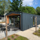 Moderne lodge ved navn Berkel med terrasse, spisebord og parasol i et grønt, fredeligt område.