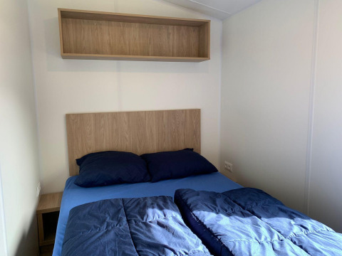 Dormitorio pequeño en la cabaña Berkel en Kaatsheuvel, Países Bajos, con una cama y estante.