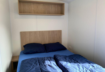 Kleine slaapkamer in de Berkel-lodge te Kaatsheuvel, Nederland, met houten bed en plank erboven.