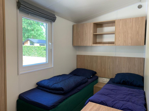 Helles Zimmer mit zwei Einzelbetten, Fenster und Holzschränken in einer Berkel Lodge in Kaatsheuvel.