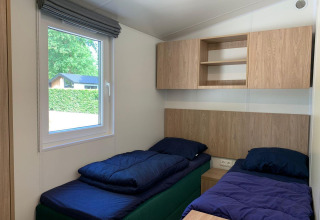 Helles Zimmer mit zwei Einzelbetten, Fenster und Holzschränken in einer Berkel Lodge in Kaatsheuvel.