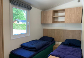 Lichte kamer met twee eenpersoonsbedden, raam en houten kasten in de Berkel Lodge te Kaatsheuvel.