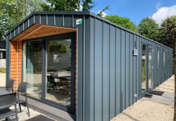 Moderne Berkel lodge in Kaatsheuvel, Nederland, met metalen wandbekleding en grote ramen, heldere dag.
