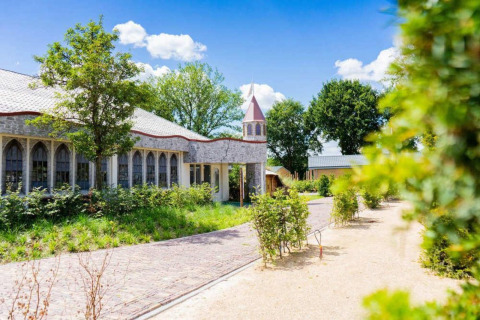 Außenansicht der Lodge Berkel in Kaatsheuvel, Niederlande, mit grüner Landschaft und blauen Himmel.