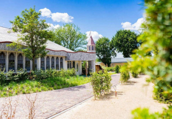 Buitenaanzicht van Lodge Berkel in Kaatsheuvel, Nederland, met veel groen en een kerkachtig gebouw.