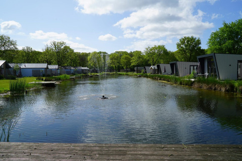 Lodges am Teich mit Springbrunnen in Berkel, Kaatsheuvel, Niederlande, an einem sonnigen Tag.