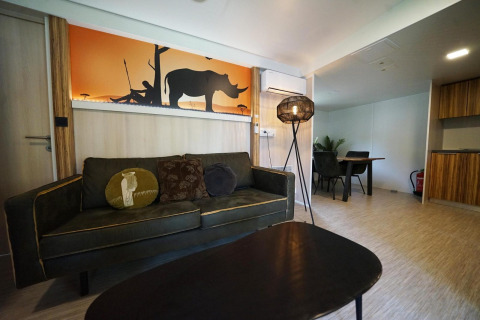 Salón en una cabaña en Kaatsheuvel, Países Bajos, con sofá, mesa y arte de pared de rinoceronte.