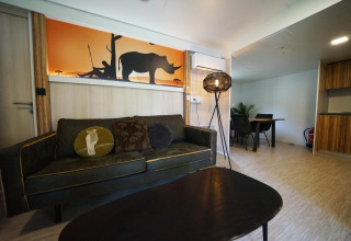 Salón en una cabaña en Kaatsheuvel, Países Bajos, con sofá, mesa y arte de pared de rinoceronte.