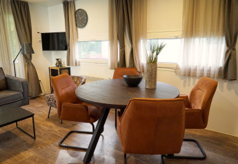 Moderne spiseplads med runde bord, orange stole og dekorative elementer i en hytte i Kaatsheuvel, Holland.