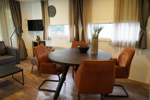 Moderne spiseplads med runde bord, orange stole og dekorative elementer i en hytte i Kaatsheuvel, Holland.