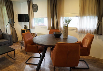 Moderne spiseplads med runde bord, orange stole og dekorative elementer i en hytte i Kaatsheuvel, Holland.