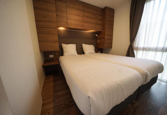 Habitación moderna en Cottage at Kaatsheuvel, Países Bajos, con dos camas, muebles de madera y gran ventana.