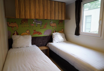 Kinderkamer met twee eenpersoonsbedden, dierenmuur en raam in Cottage lodge in Kaatsheuvel, Nederland.