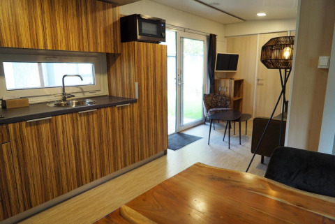 Moderne lodge i Kaatsheuvel, Holland, med træinventar, tekøkken, spisebord og hyggeligt opholdsområde.