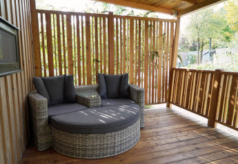 Terrasse med moderne sofa på Cottage at Kaatsheuvel, Nederlandene, omgivet af træpaneler og natur.