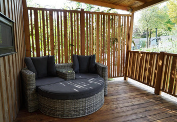 Terrasse med moderne sofa på Cottage at Kaatsheuvel, Nederlandene, omgivet af træpaneler og natur.