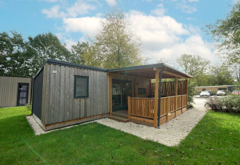 Træhytte med overdækket terrasse og haveområde ved Cottage at Kaatsheuvel, Holland, på en solrig dag.