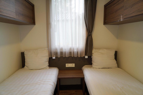 Dos camas individuales con sábanas blancas en una habitación acogedora de Cottage at Kaatsheuvel, Países Bajos.