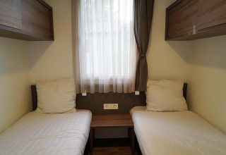 Dos camas individuales con sábanas blancas en una habitación acogedora de Cottage at Kaatsheuvel, Países Bajos.