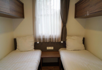 Dos camas individuales con sábanas blancas en una habitación acogedora de Cottage at Kaatsheuvel, Países Bajos.