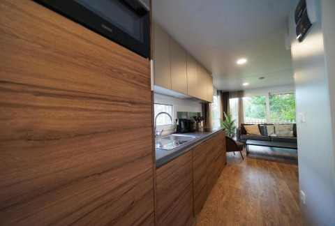 Modern kitchen and living area in Cottage at Kaatsheuvel, Netherlands, featuring wood interiors and large windows.