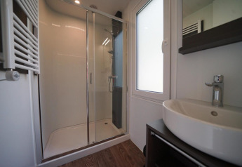 Baño moderno con ducha de vidrio y lavabo en una cabaña de Cottage at Kaatsheuvel, Países Bajos.