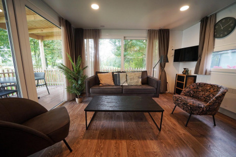 Sala en Cottage en Kaatsheuvel, Países Bajos, con muebles modernos y grandes ventanales al exterior.