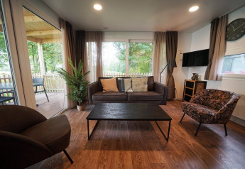 Sala en Cottage en Kaatsheuvel, Países Bajos, con muebles modernos y grandes ventanales al exterior.