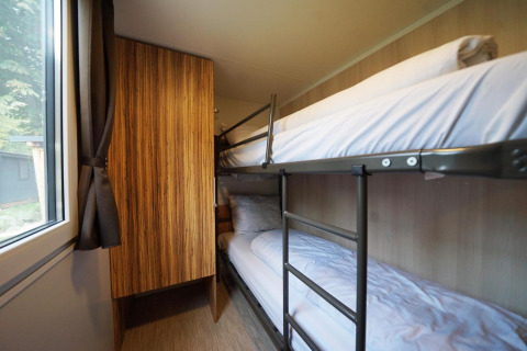 Habitación con literas, armario de madera y ventana en Cottage en Kaatsheuvel, Países Bajos.