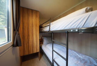 Et værelse med køjesenge, træskab og vindue i Cottage ved Kaatsheuvel, Holland, komfortabelt opstillet.